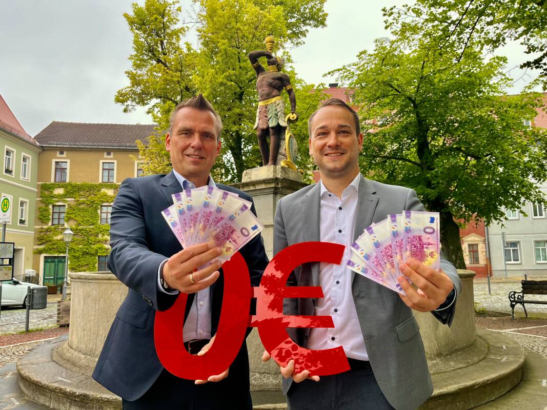 Bürgermeister Michael Kieslich (links) und Sparkassen-Filialleiter Matthias Thiele präsentieren den 0-Euro-Schein zum Stadtrechtsjubiläum.